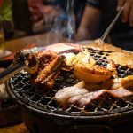 Group of people eating korean barbecue yakiniku in restaurant